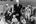 zwart-wit foto, Maurice Pata zit op een stadbankje met een groep kinderen om zich heen