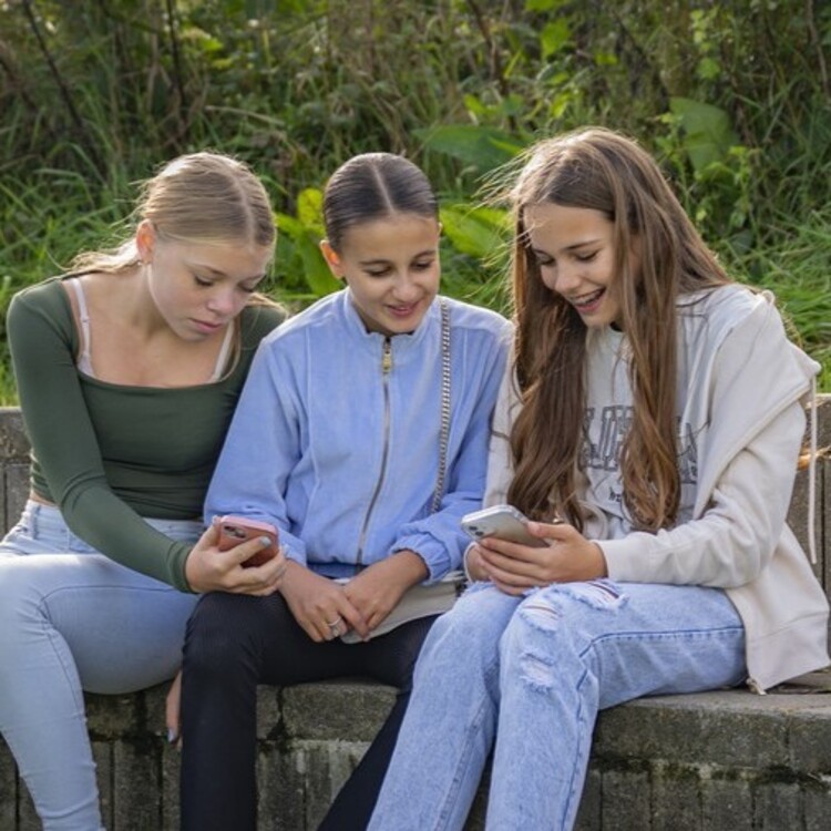 drie meisjes kijken samen op hun telefoons